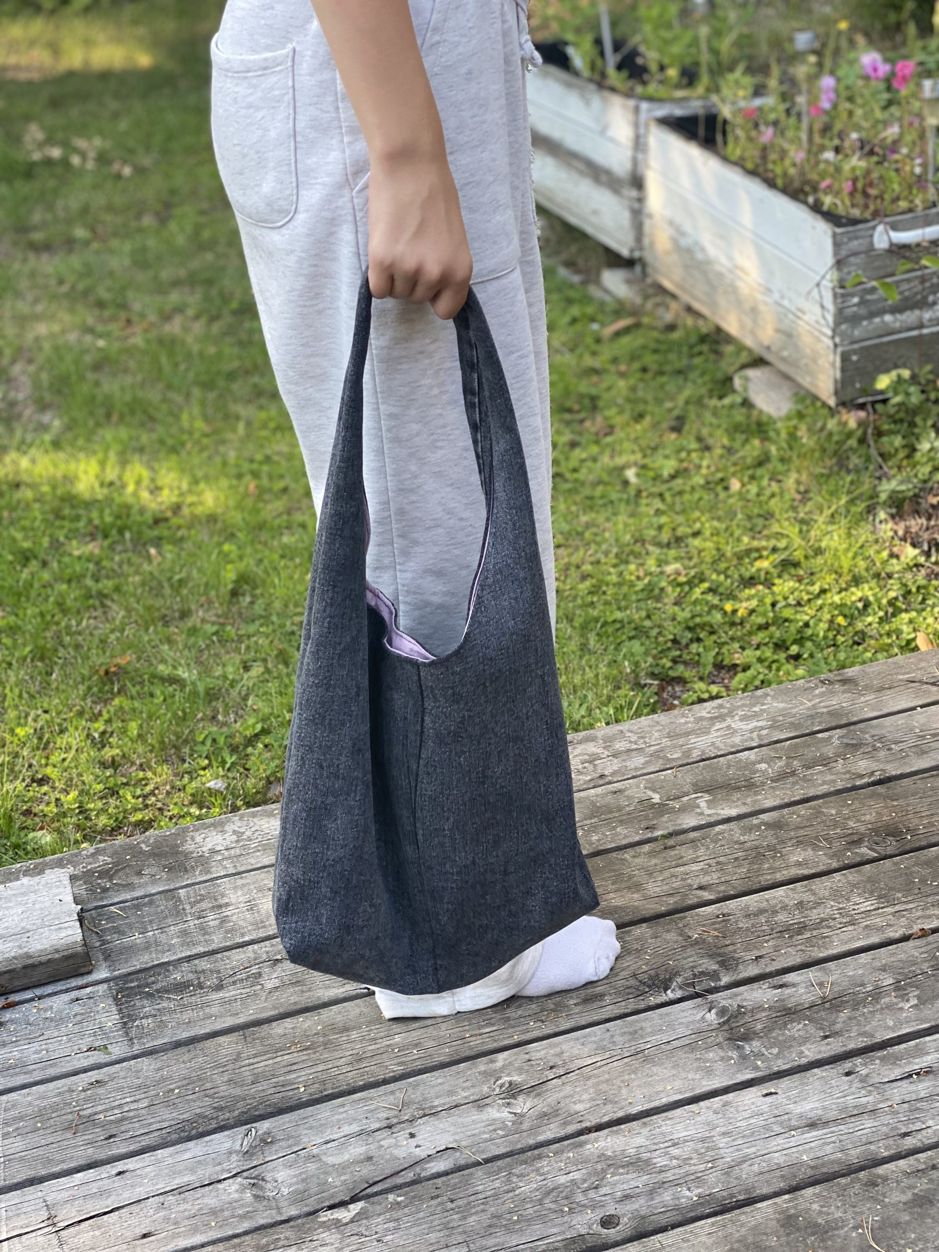 en person håller i en hemmasydd väska av jeanstyg